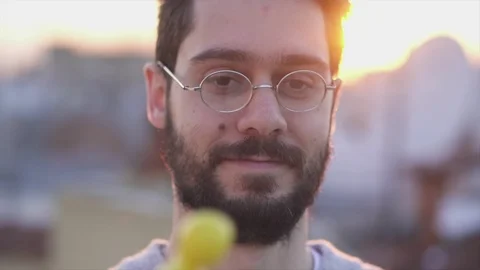Juggler, Young Man Juggling with three funny eyes toys on a rooftop sunset ti Stock Footage 106724199