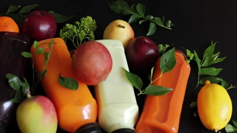 Juice bottles in yellow and dark colors surrounded by fresh fruits emphasize Stock-Footage 290482295