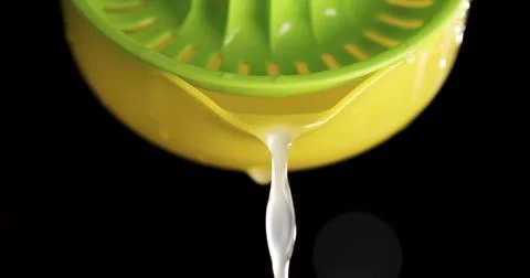 Juice dripping from a green lemon squeezer in a black Stock Photos