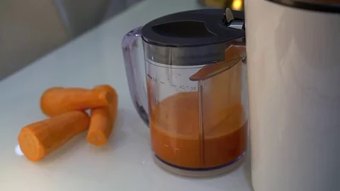 Juice extractor stands on the table and squeezes juice into a measuring tank Video stock 82725973