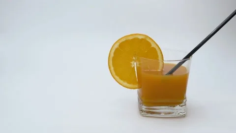 The juice from a full glass is absorbed through a black straw - slow motion Stock Footage 145813120
