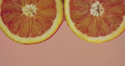 Juice or water flowing on two natural bio orange fruits on pink studio Stock Footage 150964066