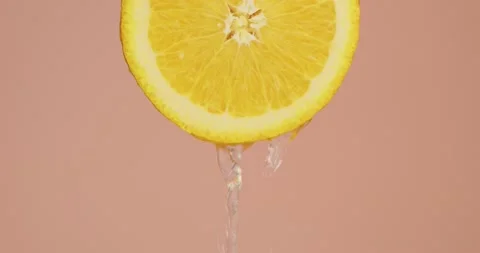 Juice or water flows down on natural orange citrus fruit on pink studio Video stock 150963343