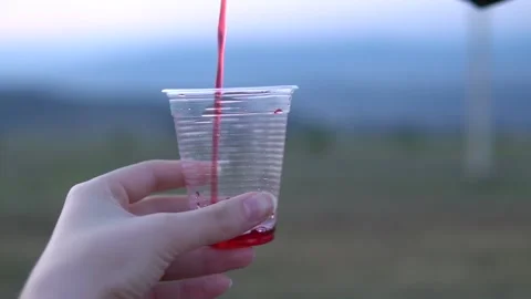 Juice pouring in plastic cup close up slow motion shot Stock Footage 139339224