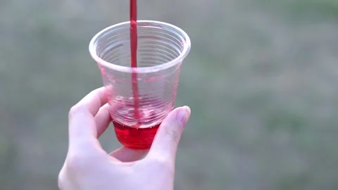 Juice pouring in plastic cup, slow motion Stock Footage 139339199