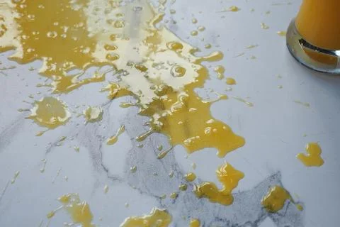 Juice spilled on a marble surface in a kitchen setting Stock Photos