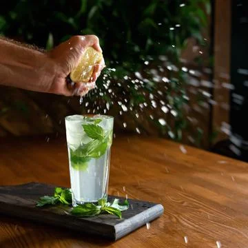 Juice splashes or drops in motion. Man squeezing lemon juice into glass with Stock Photos