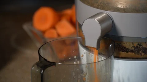 Juice squeezer processing a carrot into a liquid in a glass Stock Footage 128518042