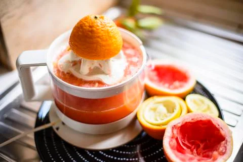 Juicer with citrus fruit squeezed in the kitchen Stock Photos