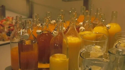Juices in glass bottles during a conference. Orange and yellow red. Lunch break. Stock Footage