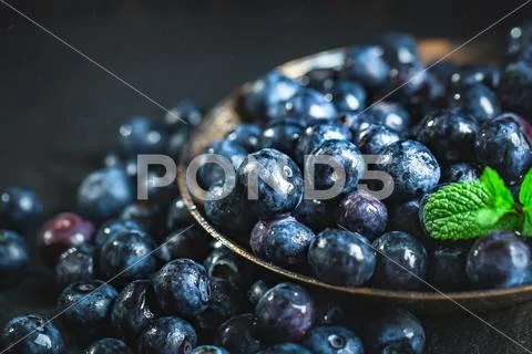 Juicy and fresh blueberries with green leaves on rustic table. Blueberry anti Stock Photos