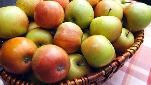 Juicy apples in a wicker basket on the table. The table is covered with a square Stock Footage 107484144