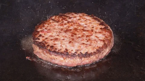 Juicy beef burger is being fried on the hot iron in UHD Video stock 95708526