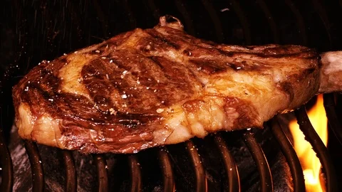 Juicy beef steak being roasted on a barbecue grill in UHD Stockbeeldmateriaal 95595862