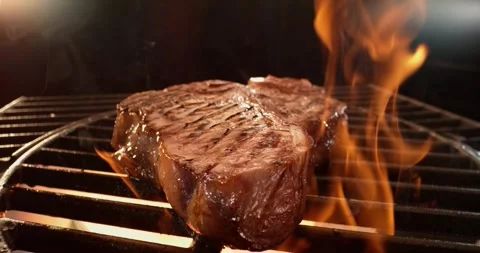 Juicy beef steak grilling on fire with dynamic flames and smoke in slow mot.. Stock Footage 337448016