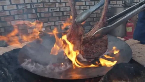 Juicy Beef Steaks Grilling over Open Wood Fire with Intense Flames and Smoke Stock Footage 338211720