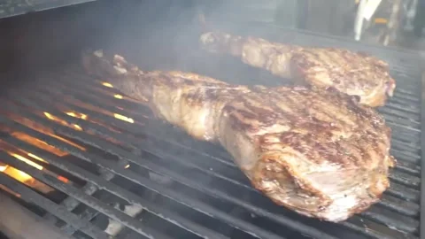 Juicy Beef Steaks Grilling on a Professional Barbecue with Rising Smoke Stockbeeldmateriaal 338213214