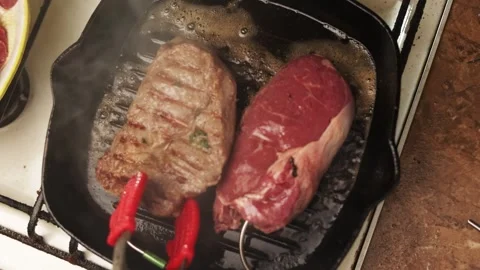 Juicy beef steaks sizzling and searing in a hot cast iron grill pan Video stock 340562868