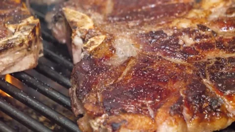 Juicy Bone-in Tomahawk Steak Sizzling on a Charcoal BBQ Grill Vídeos de archivo 332815149