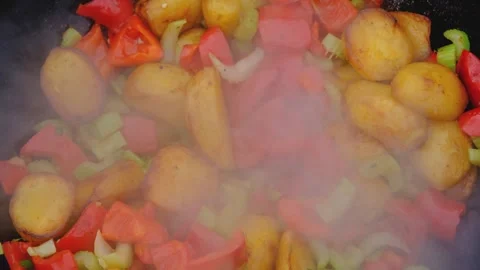 Juicy bright vegetables are fried in a cauldron over a fire. Bright vegetables Stock Footage 280929039