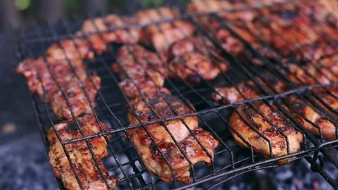 Juicy chicken pieces sizzling on a hot barbecue grill with glowing coals Stock Footage 340263835