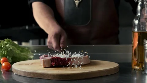 Juicy cut of beef falls onto cutting board generously seasoned Stock Footage 315231512