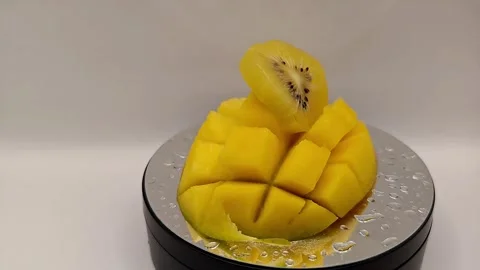 A juicy, cut yellow mango fruit is spinning on a stand. Stock Footage 325127341