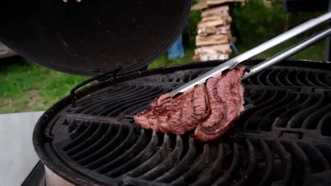Juicy fried steak is turned over on a hot grill Stock Footage 157660041