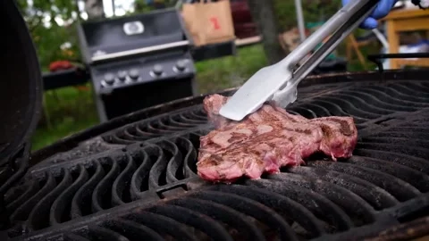 Juicy fried steak is turned over on a hot grill Stock Footage 157660054
