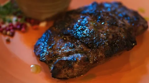 Juicy grilled beef steak on orange plate with peppercorns and sauce bowl. Stock Footage 339640205