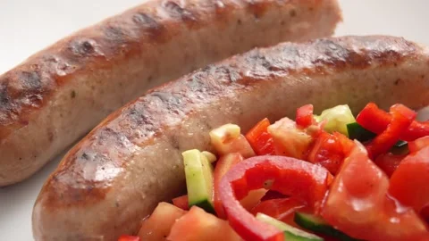 Juicy grilled Sausages rest on a pristine white Plate. Stock Footage 253903945
