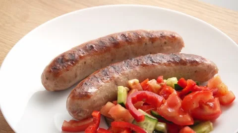 Juicy grilled Sausages rest on a pristine white Plate. Stock Footage 254523994