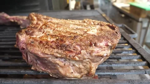 Juicy Grilled Tomahawk Steak with Charred Crust on a Barbecue Grill Stockbeeldmateriaal 338213169