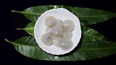 Juicy lychee flesh served in ceramic bowl with tropical foliage background Stock Footage 337455343