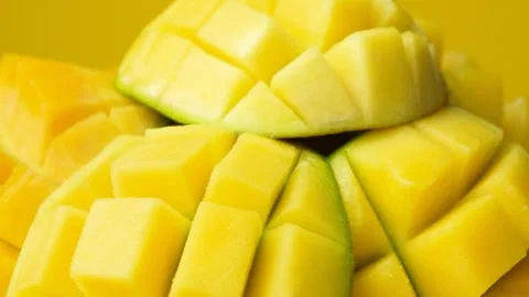 Juicy mango halves with cube cut pattern close-up rotation on yellow background Video stock 325885509