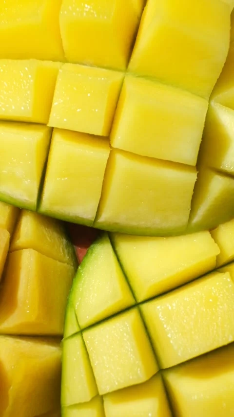 Juicy mango halves with cube cut pattern close-up rotation on yellow background Stock Footage 325886238