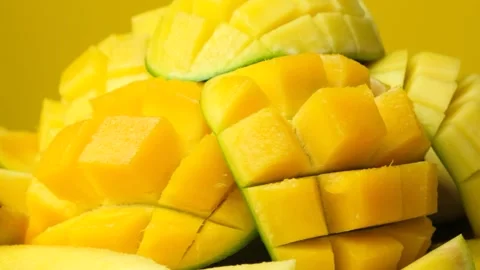 Juicy mango halves with cube cut pattern close-up rotation on yellow background Video stock 327456782