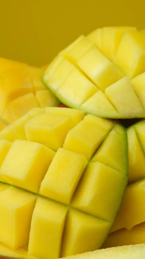 Juicy mango halves with cube cut pattern close-up rotation on yellow background Stock Footage 328010503