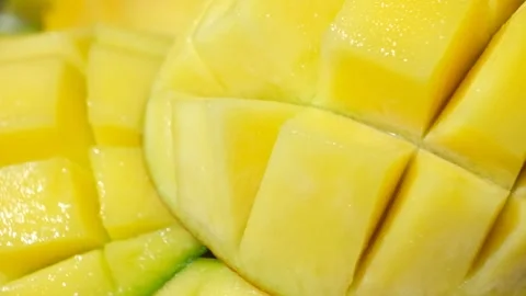 Juicy mango halves with cube cut pattern close-up rotation on yellow background Stock Footage 328361179