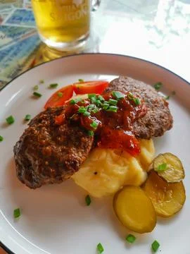 Juicy meat patty served with mashed potatoes and pickles Stock Photos