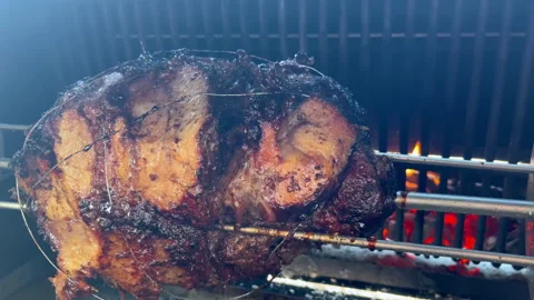 Juicy meat rotates on a spit over hot coals during grilling, briefly jerking Stock Footage 327533823