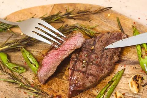Juicy medium Beef Rib Eye steak slices on wooden board with fork and knife. Stock Photos