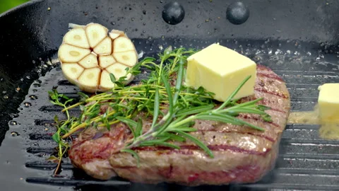A juicy medium-rare beef steak is being cooked in a cast iron skillet. Stock Footage 315904407