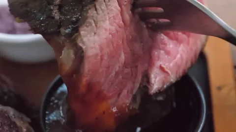Juicy Medium-Rare Roast Beef Dipped into Savory Au Jus Sauce Close-Up Stock Footage 338211703