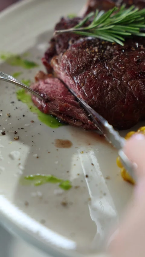 Juicy Medium Rare Steak Being Sliced on Plate With Rosemary and Corn Vídeos de archivo 338010268