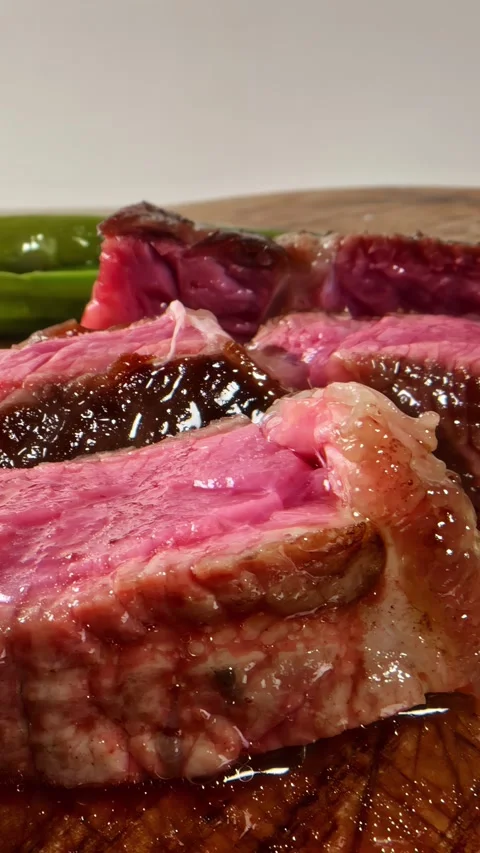 Juicy Medium-Rare Steak Slices on Wooden Cutting Board Stock Footage 336394942