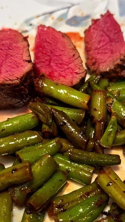 Juicy Medium-Rare Steak Slices with Sautéed Green Beans on Plate Stock Footage 339033348