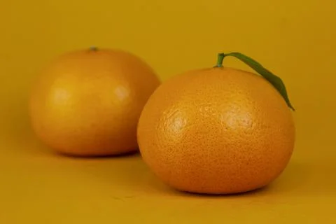 Juicy Orange fruit with leaf isolated on yellow background Stock Photos