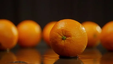 Juicy orange spins, forming waves under it. Stock Footage 267032201