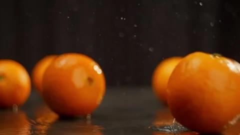 Juicy oranges fall on the table and form splashes. Stock Footage 267032154